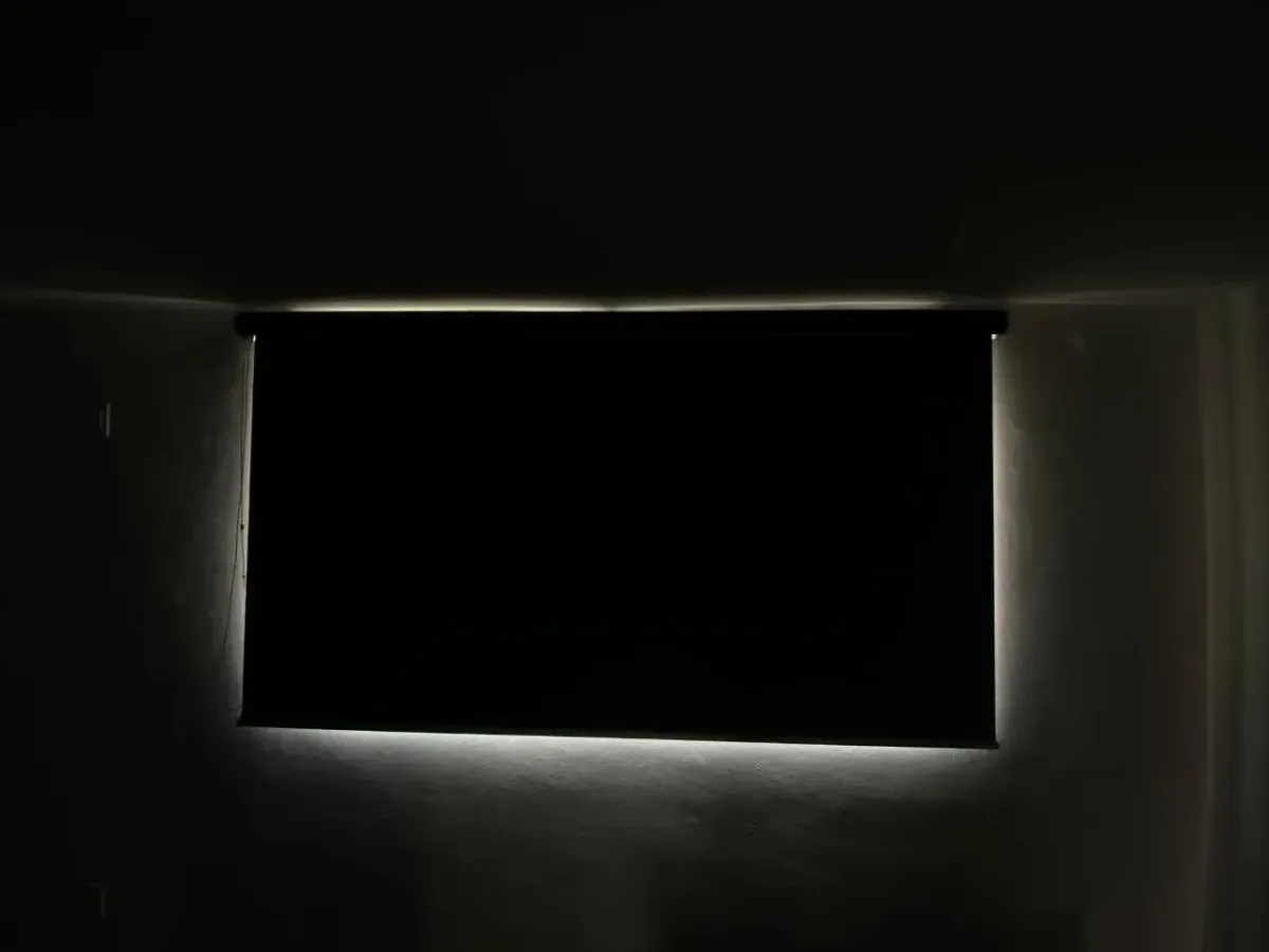 Persiana blackout cerrada en una recámara a oscuras; solo se ve una línea de luz en los bordes