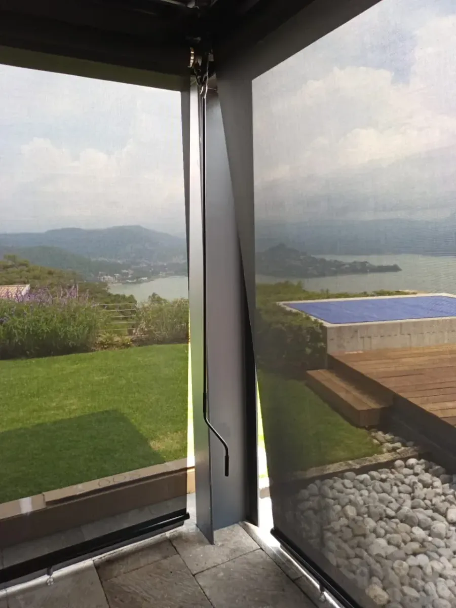 Persiana screen en un ventanal con vista al lago, el jardín y las montañas